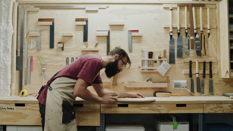 Person sanding a wooden board in a woodworking atelier