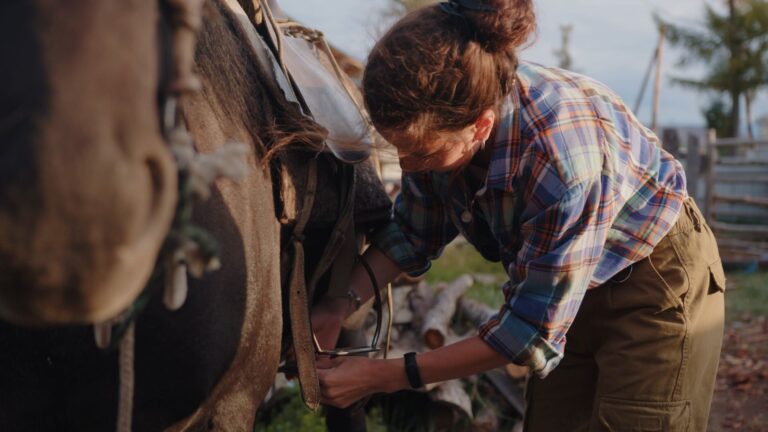Woman adjusting the straps of a saddle on a horse